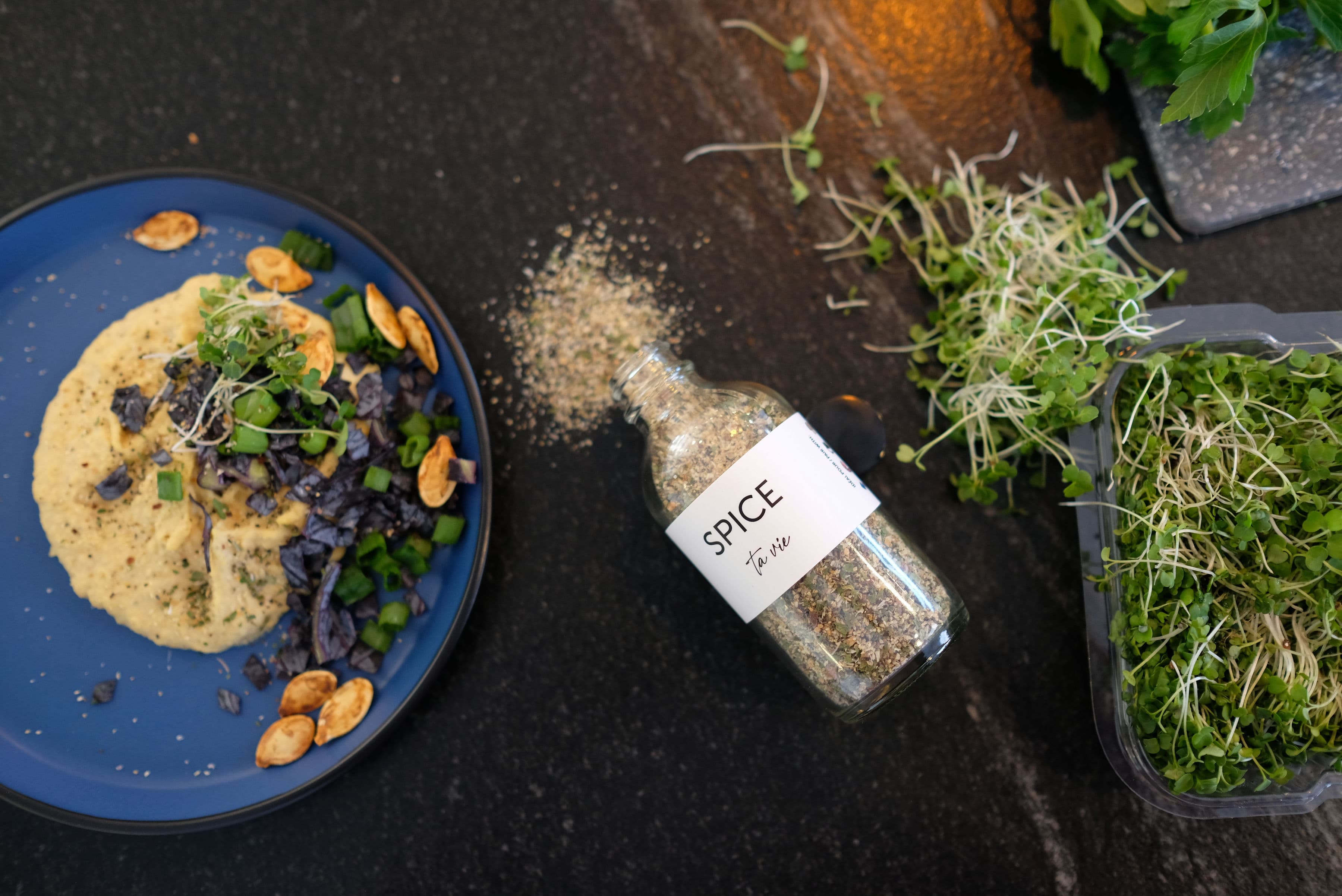 Une pincée de Spice ta vie sur une assiette gourmande, entourée de pousses fraîches