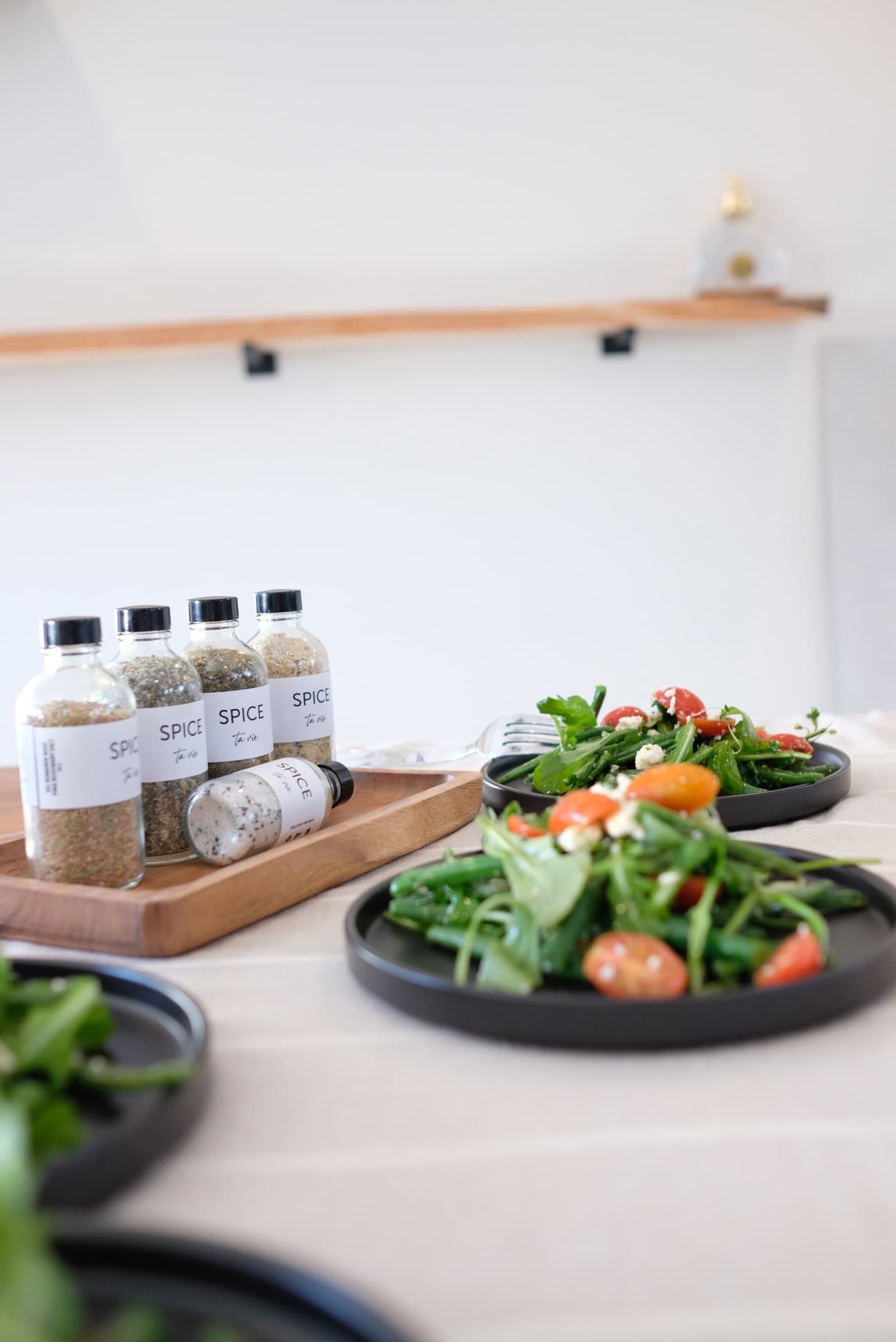 Pots Spice ta vie présentés sur un présentoir en bois, entourés de mets